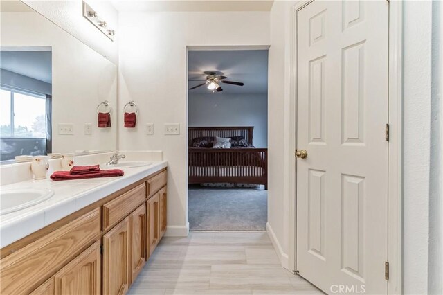 bathroom with tile flooring, double sink vanity, and ceiling fan