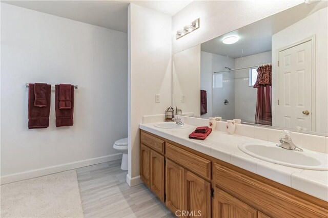 bathroom featuring toilet, tile floors, and dual vanity