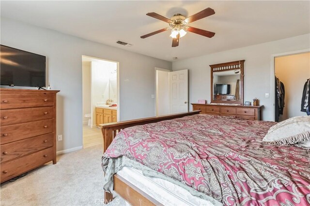 bedroom featuring a spacious closet, ensuite bath, ceiling fan, a closet, and carpet