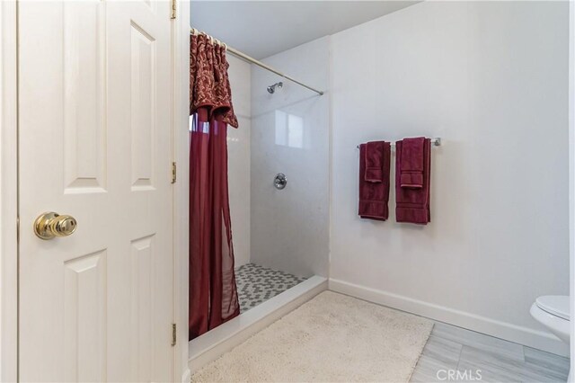 bathroom featuring walk in shower, toilet, and tile flooring