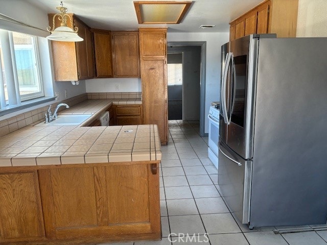 kitchen featuring kitchen peninsula, stainless steel fridge, tile countertops, white electric stove, and sink