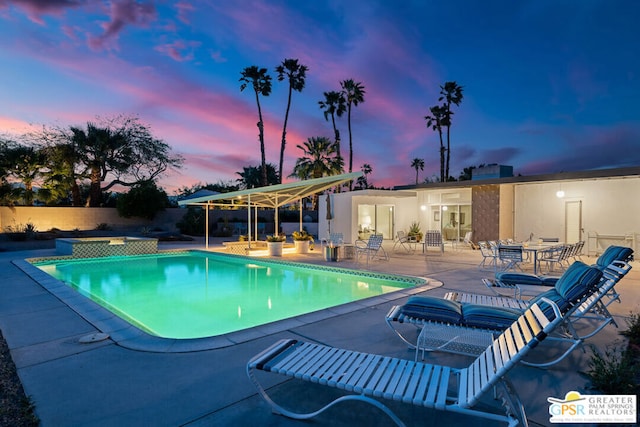 pool at dusk with an in ground hot tub and a patio area