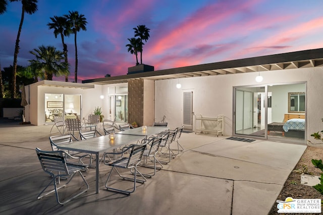 back house at dusk featuring a patio