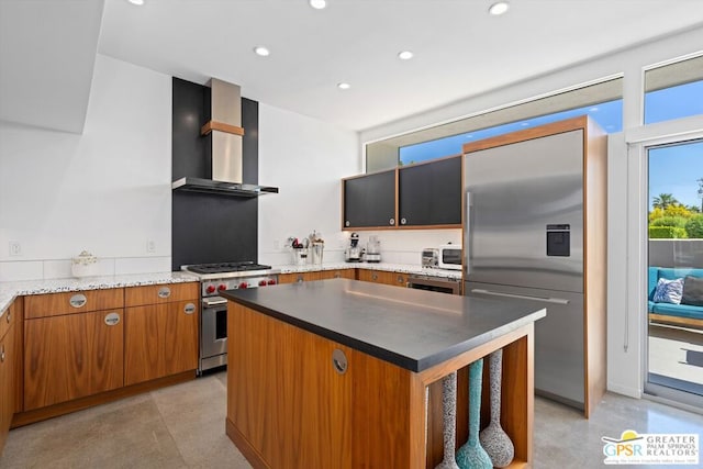 kitchen with wall chimney exhaust hood, a kitchen island, and high end appliances