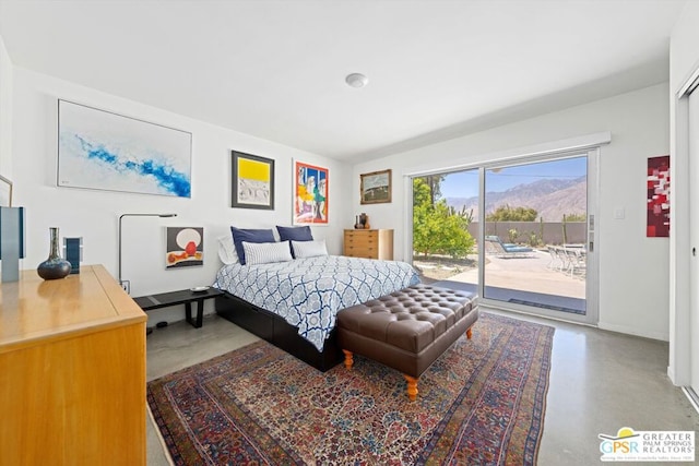 bedroom featuring a mountain view, access to exterior, and concrete flooring