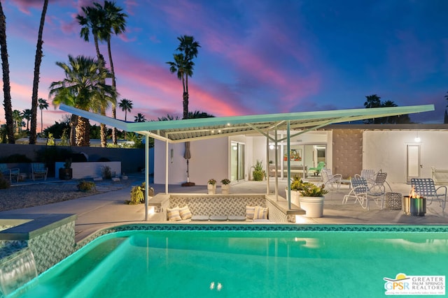 pool at dusk featuring a patio area