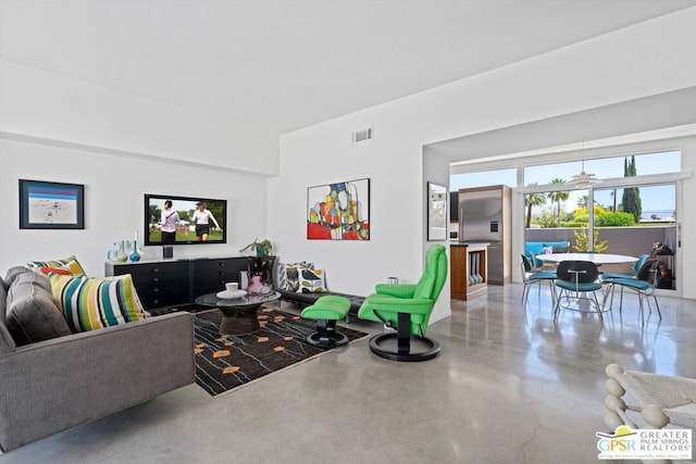 living room featuring ceiling fan and concrete flooring