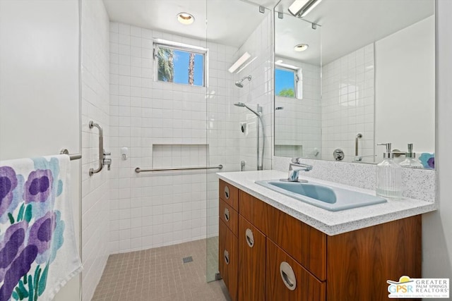 bathroom with tiled shower, vanity, and tile patterned floors