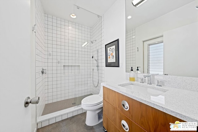 bathroom featuring vanity, toilet, and tiled shower