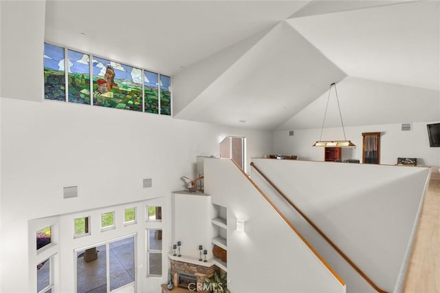 interior space with lofted ceiling, a stone fireplace, and visible vents