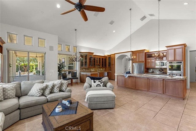 living room with light tile patterned floors, visible vents, arched walkways, and ceiling fan with notable chandelier