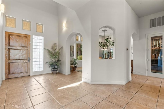 entryway featuring light tile patterned floors, arched walkways, and visible vents