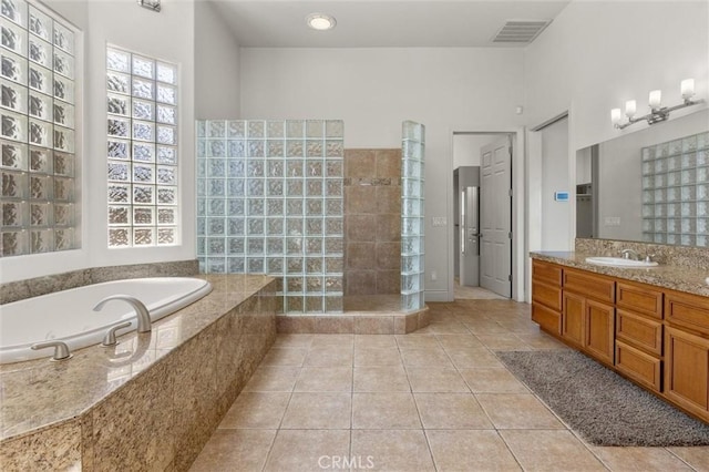 bathroom with tile patterned flooring, visible vents, a garden tub, and vanity