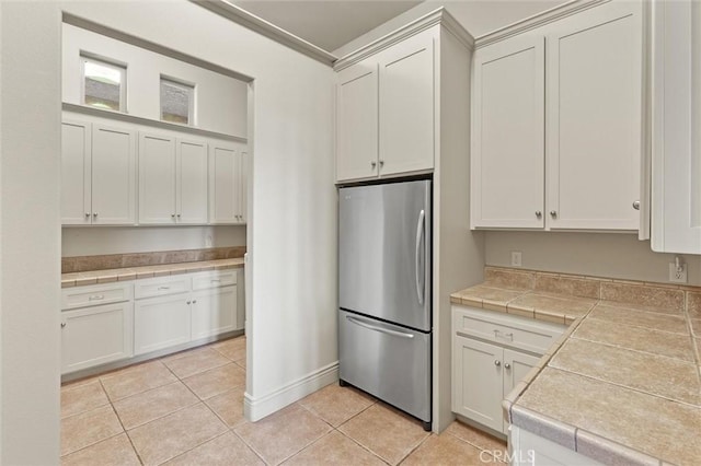 kitchen with tile countertops, light tile patterned floors, white cabinets, and freestanding refrigerator