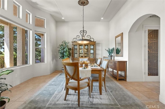 dining area featuring baseboards, arched walkways, and light tile patterned flooring