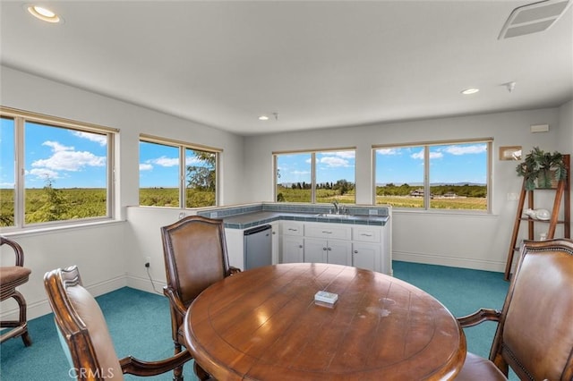 carpeted dining room featuring baseboards, visible vents, a sink, and recessed lighting