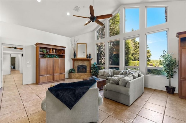 living area featuring high vaulted ceiling, a wealth of natural light, a glass covered fireplace, and visible vents