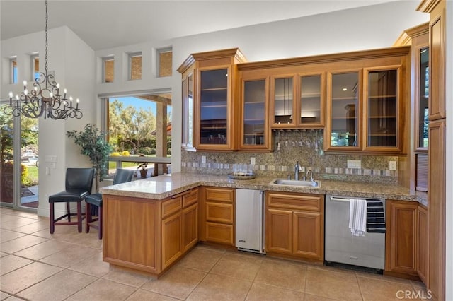 kitchen featuring glass insert cabinets, dishwasher, backsplash, and a sink