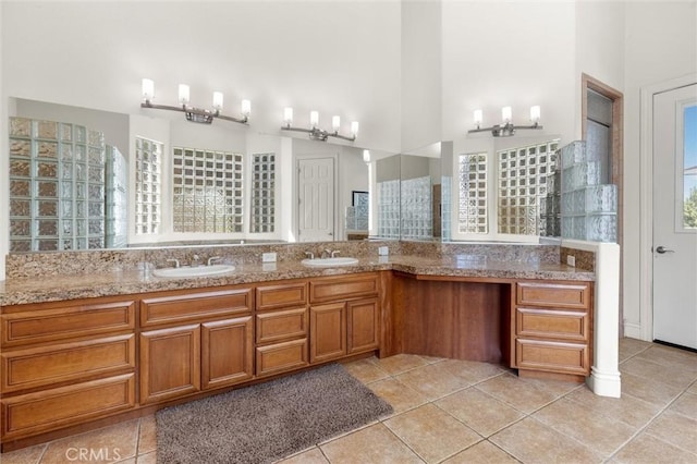 full bath with double vanity, a high ceiling, tile patterned flooring, and a sink