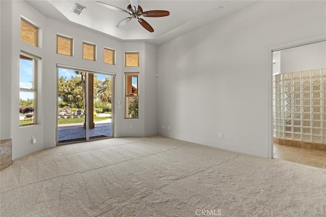 spare room featuring baseboards, visible vents, a ceiling fan, and light colored carpet