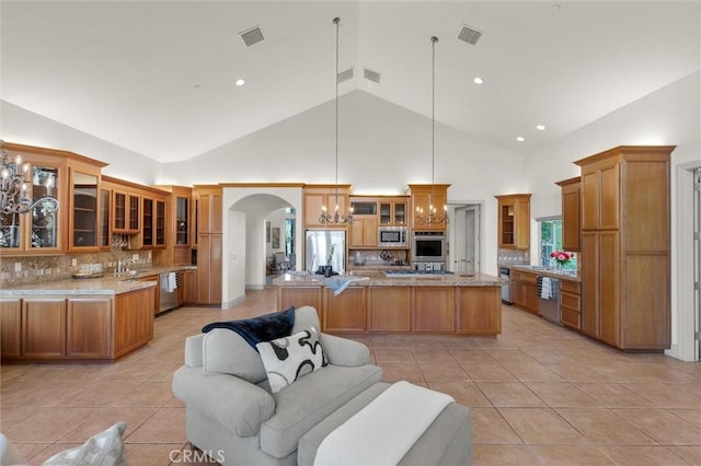 kitchen with glass insert cabinets, brown cabinetry, decorative light fixtures, and appliances with stainless steel finishes