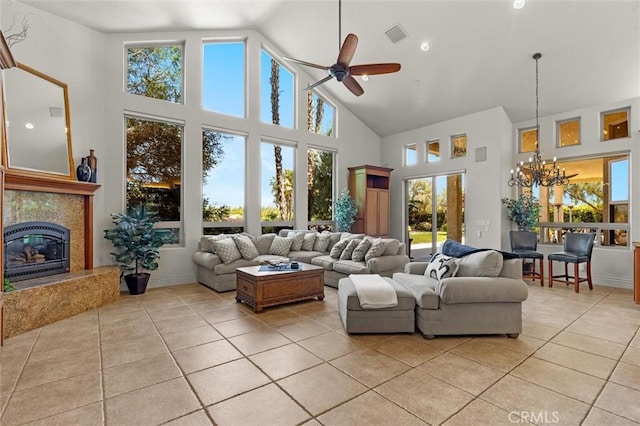 living area featuring light tile patterned floors, ceiling fan with notable chandelier, high vaulted ceiling, and a high end fireplace