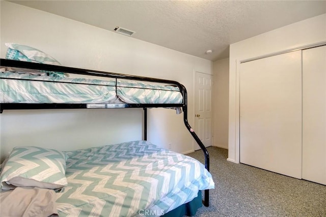 carpeted bedroom with a closet and a textured ceiling