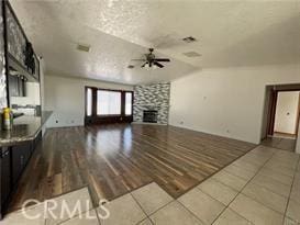 unfurnished living room featuring hardwood / wood-style flooring, a fireplace, a textured ceiling, and ceiling fan