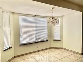 unfurnished dining area featuring an inviting chandelier and light tile patterned flooring