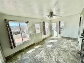 unfurnished sunroom featuring ceiling fan