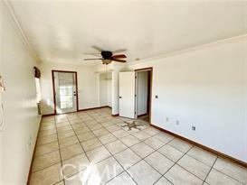 tiled spare room with crown molding and ceiling fan