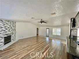 unfurnished living room featuring hardwood / wood-style floors, a stone fireplace, and a textured ceiling