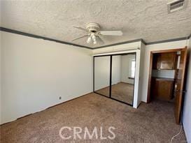 unfurnished bedroom featuring carpet floors, ornamental molding, a closet, and ceiling fan