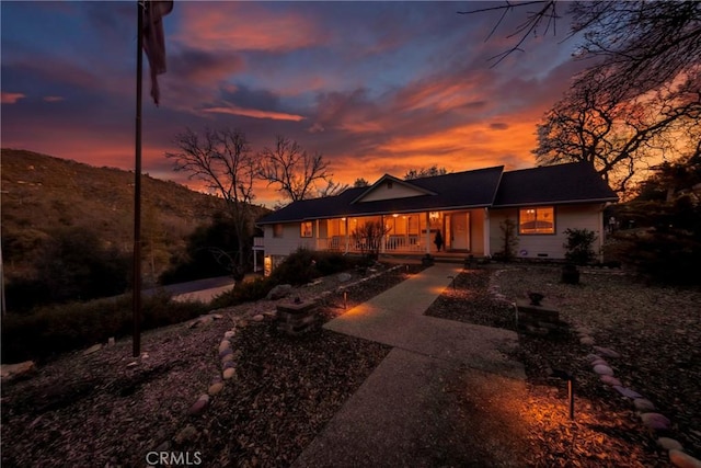 back of property at dusk featuring covered porch and crawl space