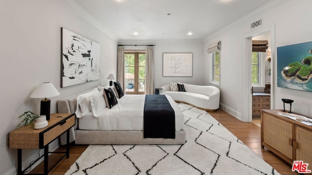 bedroom with access to exterior, connected bathroom, light hardwood / wood-style flooring, and ornamental molding