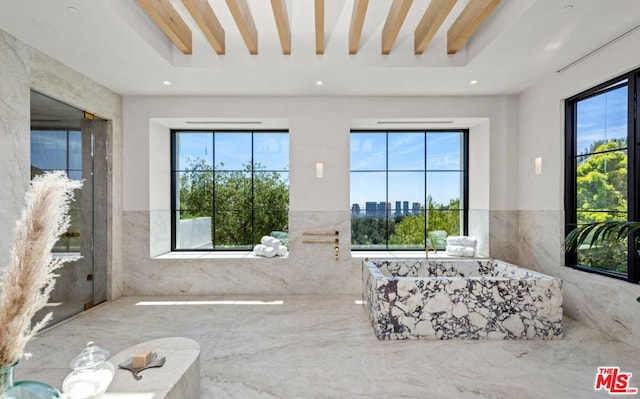 bathroom featuring tile walls, beamed ceiling, and a bath