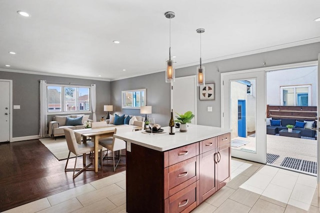 kitchen featuring ornamental molding, a center island, light wood-type flooring, and decorative light fixtures