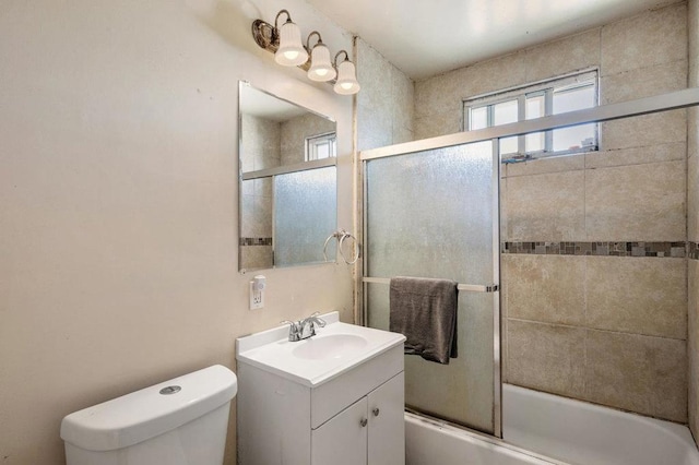 full bathroom with enclosed tub / shower combo, vanity, and toilet