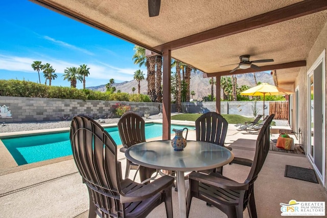 view of patio / terrace with a fenced in pool, ceiling fan, and a mountain view