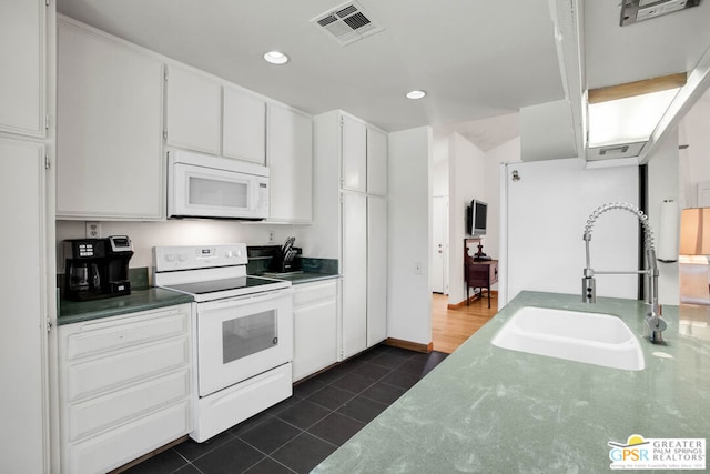 kitchen with white cabinetry, sink, dark tile patterned floors, and white appliances