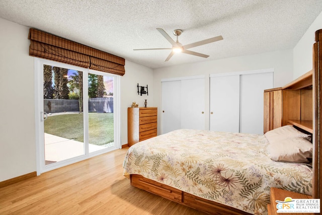 bedroom with a textured ceiling, two closets, access to outside, light wood-type flooring, and ceiling fan