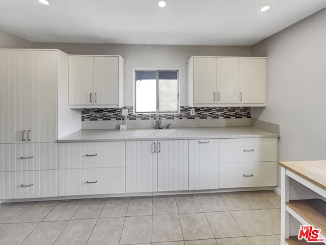 kitchen with white cabinets, light tile patterned floors, sink, and tasteful backsplash