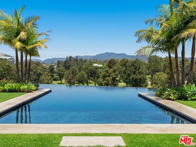 view of swimming pool with a water and mountain view