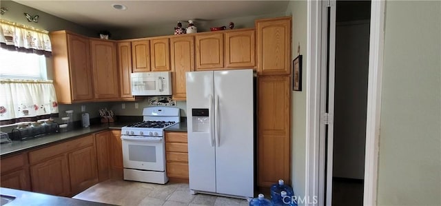 kitchen featuring brown cabinetry, dark countertops, and white appliances