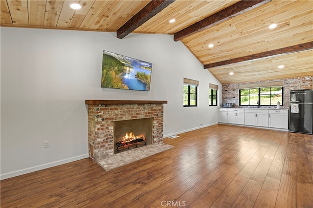 unfurnished living room with a fireplace, beamed ceiling, hardwood / wood-style floors, and wooden ceiling