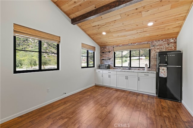 kitchen with vaulted ceiling with beams, wooden ceiling, wood-type flooring, and black refrigerator