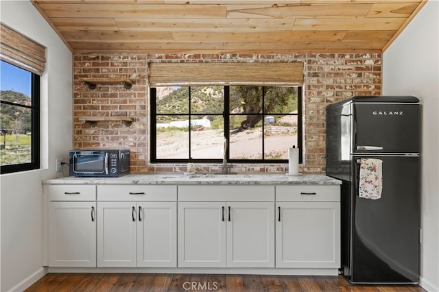 bar featuring dark hardwood / wood-style floors, wooden ceiling, black appliances, and vaulted ceiling