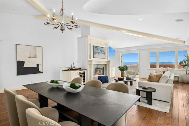 dining room with lofted ceiling with beams, a wealth of natural light, a lit fireplace, and hardwood / wood-style floors