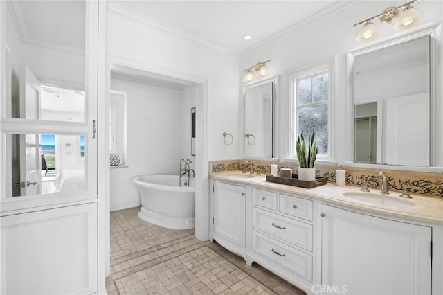 full bath featuring double vanity, a soaking tub, ornamental molding, and a sink