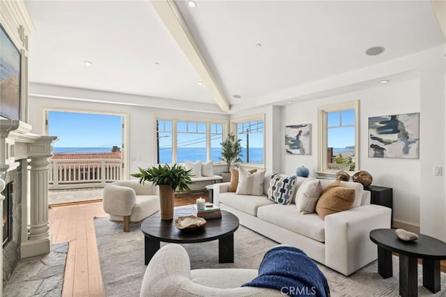 living room with light wood-style floors, recessed lighting, beamed ceiling, and a premium fireplace